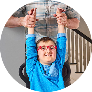 A smiling child with his arms held upright by an adult