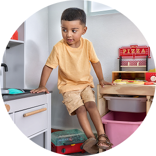 A young child playing with a toy kitchen