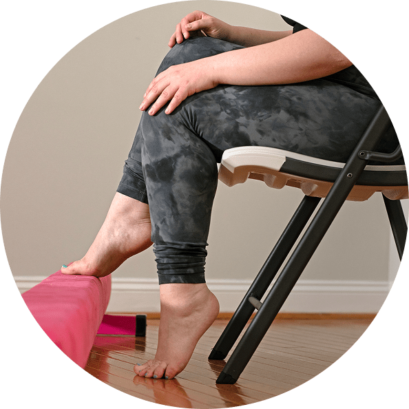 A person seated doing foot and leg exercises on a pink bar